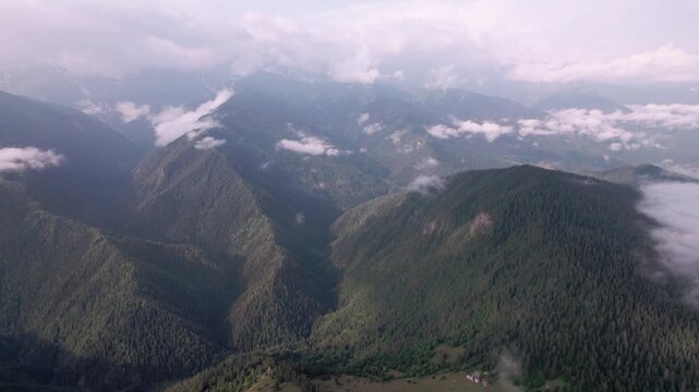 Cinematic drone flight above lush green Caucasus mountains, drifting clouds in Svaneti, Georgia. Peaceful aerial landscape for travel films, meditation, relaxation, wellness nature projects