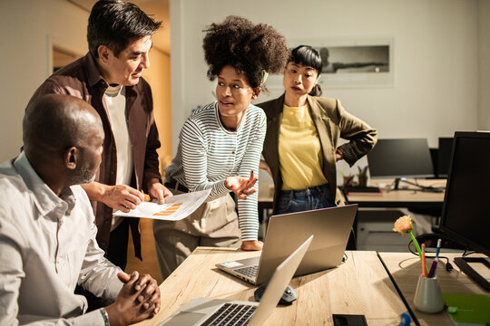 Diverse coworkers collaborating on project in modern office