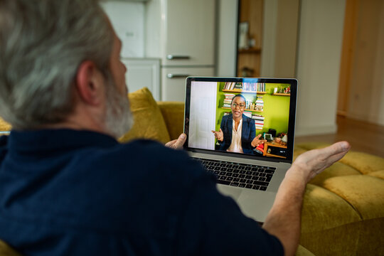 Senior man talking to therapist online at home