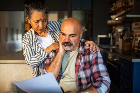 Worried couple reviewing bills in home kitchen