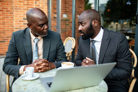 Two businessmen meeting with laptop at outdoor cafe