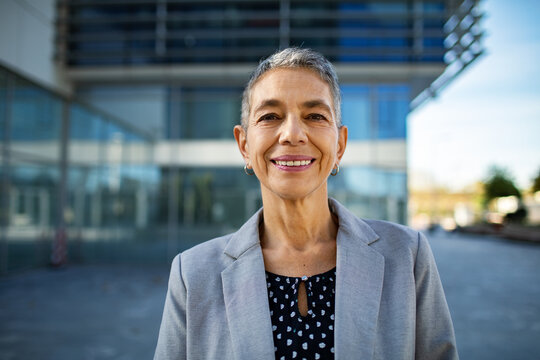 Confident senior businesswoman smiling outside modern office building