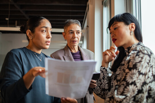 Three coworkers reviewing a document in a modern office
