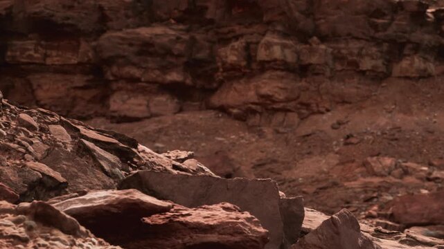 Large rocks are present in a barren landscape with varied textures and colors. The ground is dry and rocky, with no signs of plants or water. The setting highlights natural features.