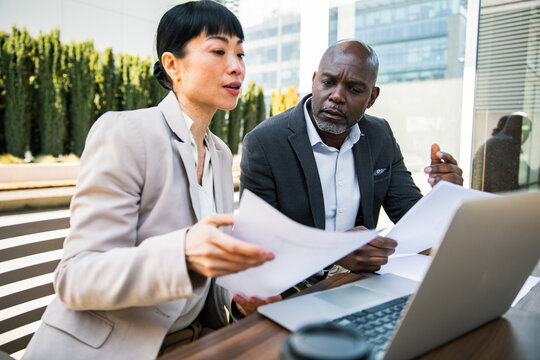 Two business professionals reviewing documents on outdoor office terrace