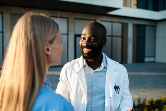 Smiling doctor talking with patient outside hospital