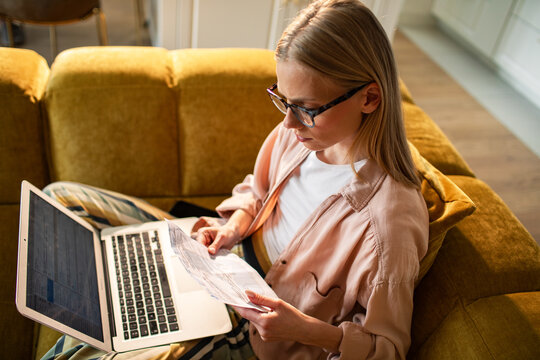 Woman reviewing household bills on laptop at home