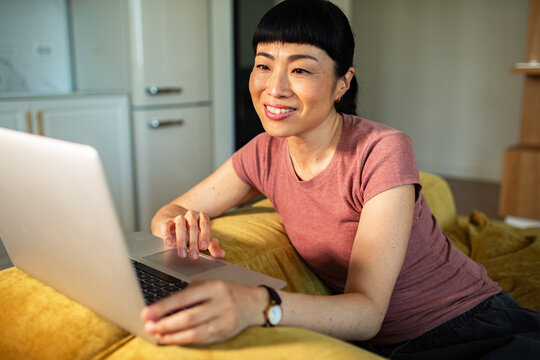 Smiling woman using laptop on sofa at home