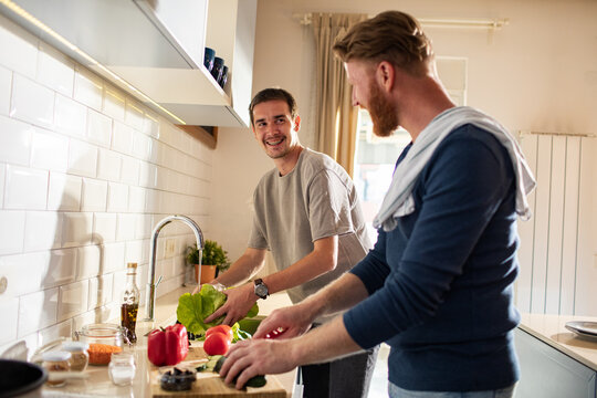 Two men cooking fresh vegetables in home kitchen