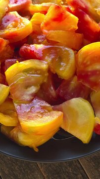 Close-up of chunks of large Old German tomato on a plate. Warm afternoon light, vertical video.