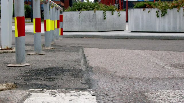 Close-up of steel safety bollards with reflective markings in an urban environment. Static infrastructure detail featuring metal traffic posts, pavement and modern city streetscape with shallow depth 