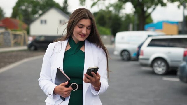 Beautiful young business woman talking on smartphone and smiling outdoors, slow motion