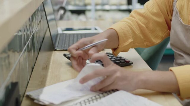 Small business owner calculating expenses with calculator and paper receipts finance accounting money budget