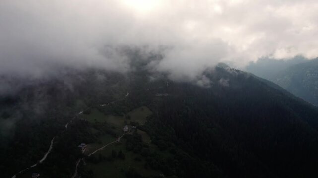 Aerial drone flight through clouds above lush green Caucasus mountains in Svaneti, Georgia. Peaceful alpine landscape with forested peaks, perfect for meditation, relaxation, travel and nature project
