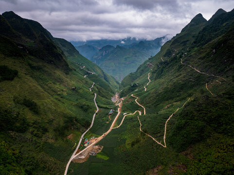 Aerial view of the winding mountain roads through the lush green valley of Ma Pi Leng Pass in Meo Vac, Ha Giang, Vietnam.