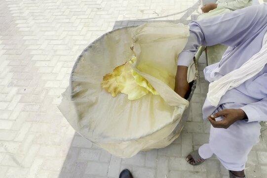 Street vendor sprinkling spice on traditional fried papadum snacks served outdoors in South Asia