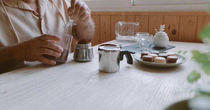 Man making coffee at home, putting ground coffee into moka pot. Preparation home coffee, morning ritual, coffee brewing process.