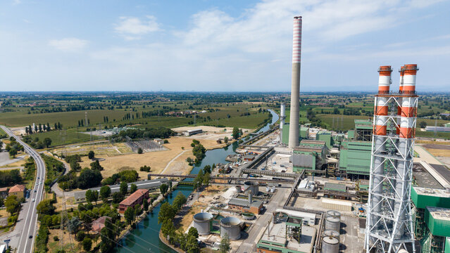 Aerial view of the Terna Tavazzano power plant with its tall chimneys and industrial facilities situated near a canal in the rural landscape of Montanaso Lombardo, Lombardia, Italy.