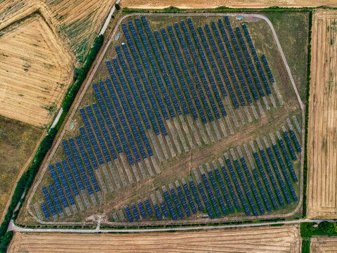 Aerial view of the solar farm at the Serravalle Logistic area, featuring rows of photovoltaic panels arranged in a field surrounded by agricultural land in Serravalle Scrivia, Piedmont, Italy.