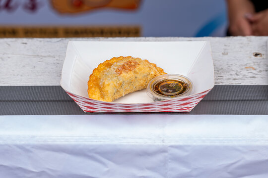 Fried empanada with dipping sauce served in a paper tray at Taste of Chicago in Chicago, Illinois, United States, July 2026.