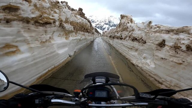 POV motorcycle ride through towering snow walls on Zagari Pass in Svaneti, Georgia. Epic mountain road adventure with breathtaking alpine scenery and a unique summer riding experience