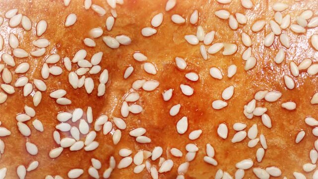 Seamless 4K looping vertical movement across a golden baked bread crust with sesame seeds creating a warm food themed background for culinary videos and creative projects.