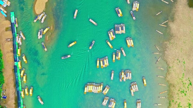 Turquoise river near Guilin, Guangxi, China, filled with bamboo rafts and small boats beside sandy banks, showcasing tourism, transport, and scenic river landscape.