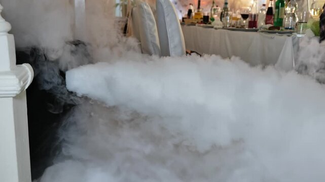 Person pouring liquid nitrogen creating decorative smoke at a restaurant event