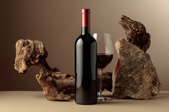 Glass and bottle of red wine with old driftwood and a piece of granite rock.