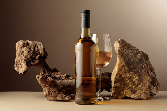 Glass and bottle of white wine with old driftwood and a piece of granite rock.