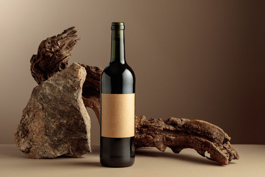 Red wine with old driftwood and a piece of granite rock on a beige background.