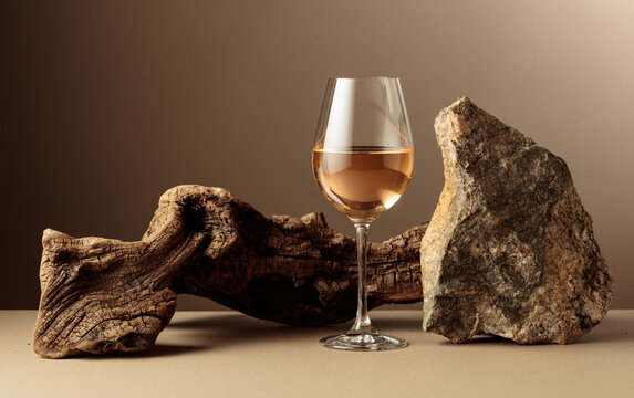 Glass of white wine with old driftwood and a piece of granite rock.