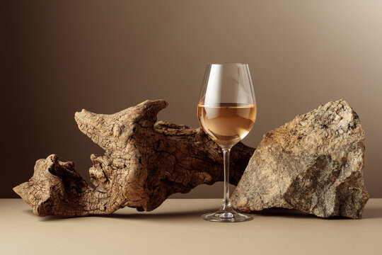 Glass of white wine with old driftwood and a piece of granite rock.