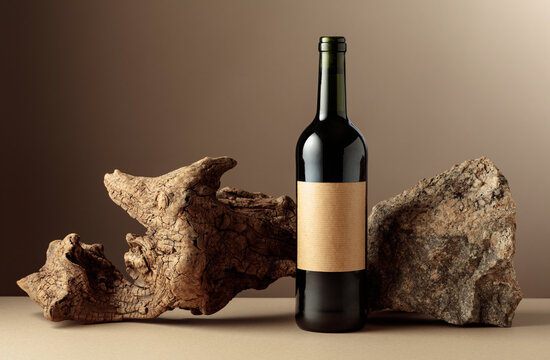 Red wine with old driftwood and a piece of granite rock on a beige background.