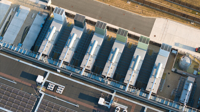 Aerial view of a hyperscale data center featuring rows of industrial cooling units and solar panels on the roof during the golden hour in Didcot, England, United Kingdom.