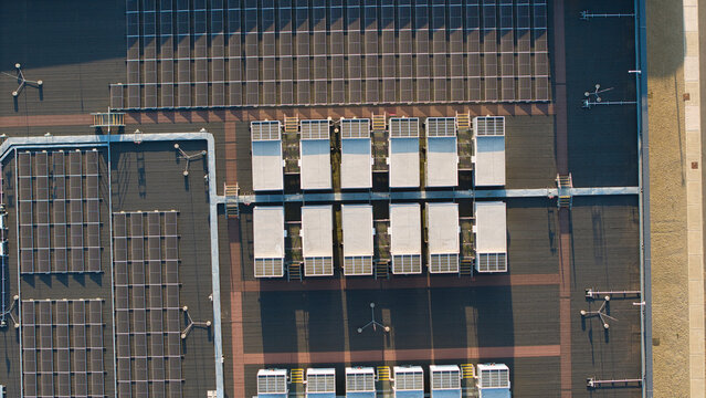 Aerial view of a hyperscale data center roof featuring rows of solar panels and industrial HVAC cooling units illuminated by warm golden hour light in Didcot, England, United Kingdom.