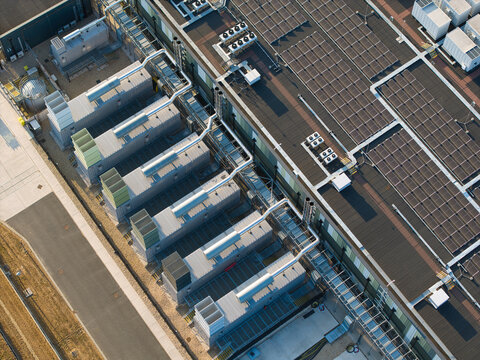 Aerial view of a hyperscale data center featuring rows of cooling units and extensive rooftop solar panels illuminated during golden hour in Didcot, England, United Kingdom.