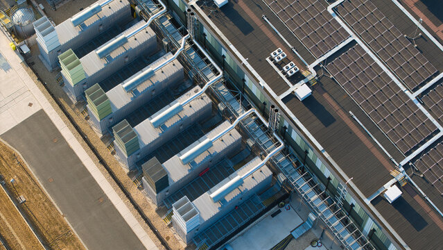 Aerial view of the Hyperscale Data Center featuring industrial cooling units and rooftop solar panels illuminated by golden hour light in Didcot, England, United Kingdom.
