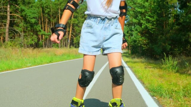 Girl is roller skating by forest, enjoying an active hobby in the open air.