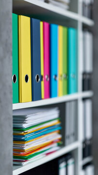 Colorful office binders and document folders on archive shelves for organized business file storage