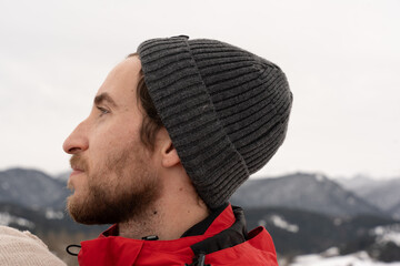 Profile portrait of young man in beanie contemplating winter mountain landscape © Laia Balart