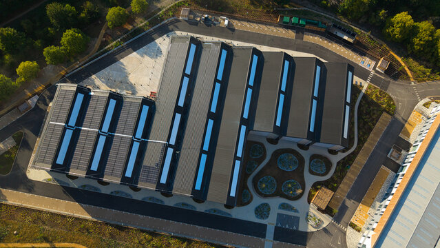 Aerial view of the modern tech foundry 3 building at Harwell Science and Innovation Campus, featuring a sawtooth roof with solar panels and skylights, in Didcot, England, United Kingdom.