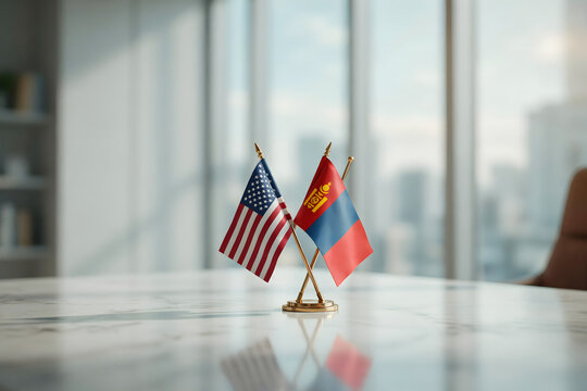 Miniature flags of the united states and mongolia standing on a white marble table in a blurred office setting for a diplomatic discussion