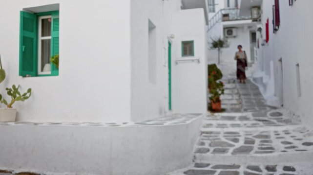 Mykonos whitewashed street with teal shutters and stone steps, defocused bokeh street; background backplate copyspace calm.