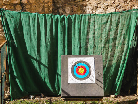 Archery target with arrows embedded in the center at an outdoor shooting range. Sports equipment for archery practice, precision training and recreational competition.