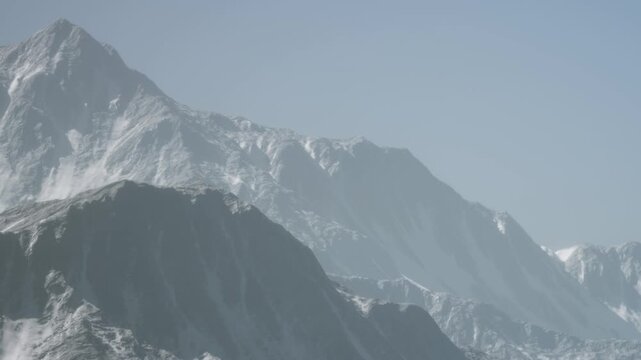 Snow covers the large peaks of mountains under bright blue skies. The scene shows the rugged terrain with sharp ridges and slopes. No signs of human activity are visible.