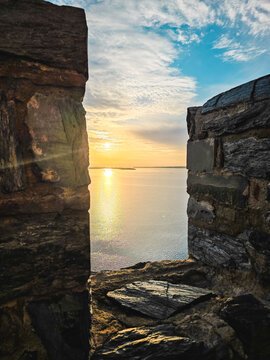 Golden sunset over the Danube River seen from the medieval walls of Ram Fortress in Serbia. Historic stone battlements and tower illuminated by warm evening sunlight.
