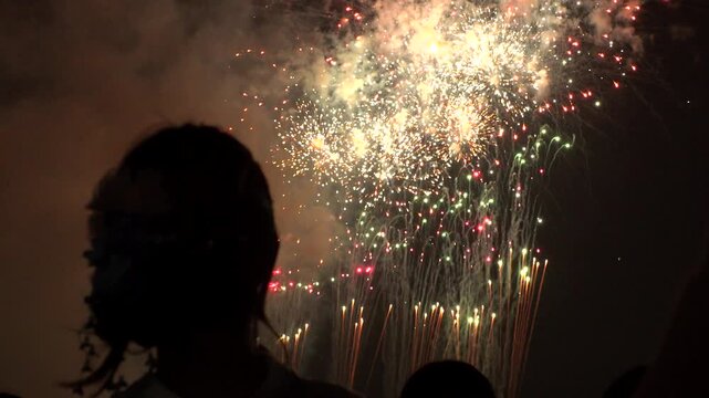 TOKYO, JAPAN - 28 JULY 2026 : Rear view of people silhouette watching fireworks show at night. Japanese romantic summer scene concept video.