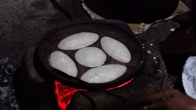 Chitai pitha is being made in a terracotta mold for making pitha in a heated clay oven. Chitai pitha is being made in a five-hole terracotta mold.