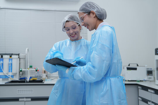 Researchers Analyzing Data with Digital Tablet in Laboratory Setting